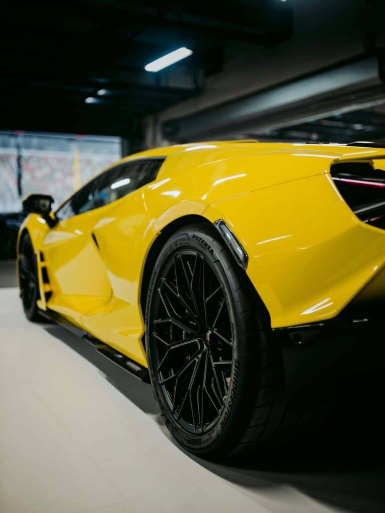 High-quality image of a sleek yellow luxury supercar parked indoors, showcasing its elegant design.